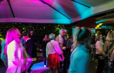 Heimat • Menschen feiern und tanzen unter buntem Licht auf der Terrasse