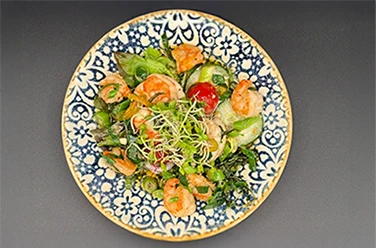 Heimat • Garnelen-Salat Heimat • Bunter Garnelen-Salat mit frischem Gemüse und Sprossen auf blau-weißem Teller.