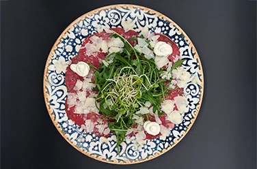 Heimat • Carpaccio mit Rucola und Parmesan Heimat • Carpaccio mit Rucola, Parmesan und Creme auf verziertem Teller